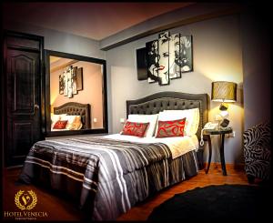 una camera da letto con un letto con cuscini rossi e uno specchio di Hotel Venecia a Huánuco