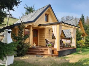una casa pequeña con porche y cenador en Domki z jacuzzi Pasja I, en Mizerna