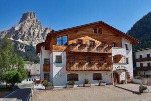 a large wooden building with a mountain in the background at Ciasa Verena in Corvara in Badia
