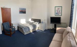 a bedroom with a bed and a couch and a television at Beeton Villas Holiday Apartments in Blackpool