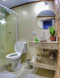 a bathroom with a toilet and a sink at Portal Sui­tes Casa do Lago in Paraty