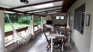 a porch with a hammock and a table and chairs at Recanto das Saíras in Morretes