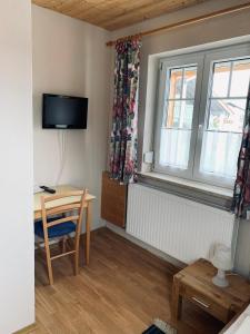 a small room with a table and a window and a desk at Pension Elisa in Lechbruck