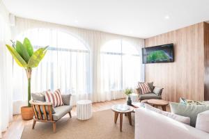 a living room with a couch and chairs and a tv at Clube Maria Luisa in Albufeira