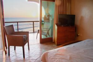 een slaapkamer met een bed, een televisie en een balkon bij Taghazout Beach in Taghazout