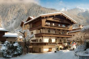 een groot gebouw in de sneeuw met bergen op de achtergrond bij Hotel Garni Villa Knauer in Mayrhofen