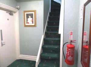 a staircase with a green carpet and a fire extinguisher at Beeton Villas Holiday Apartments in Blackpool