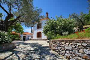 a house with a stone walkway and a stone wall at Anania Cottage in Skopelos Town