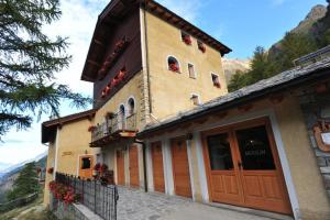 budynek z skrzyniami kwiatowymi na oknach i balkonem w obiekcie Locanda Lac Place Moulin w mieście Bionaz