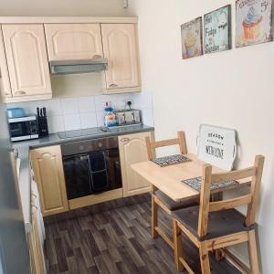 uma pequena cozinha com uma mesa de madeira e cadeiras em Be My Guest Liverpool - Ground Floor Apartment with Parking em Liverpool
