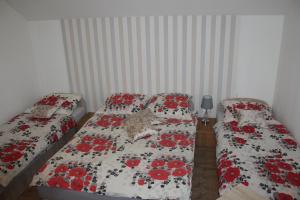 2 camas en un dormitorio pequeño con flores rojas en Domek "Madzia", en Brenna