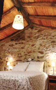1 dormitorio con cama y pared de piedra en A Casa da Natália, en Alvares