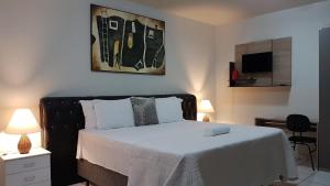 een slaapkamer met een bed met witte lakens en een televisie bij B & A Suites Inn Hotel - Quarto Luxo Platinum in Anápolis