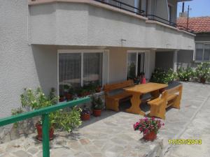 un patio con mesa de madera y bancos frente a un edificio en Panayotovi Guest House, en Byala