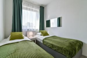 sypialnia z 2 łóżkami z zieloną pościelą i oknem w obiekcie LTC Apartments Malczewskiego Centrum w Gdańsku