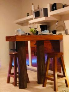 mesa de madera con 2 taburetes y microondas en Hotel El Pueblito, en Isla Holbox
