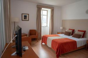 a hotel room with a bed and a flat screen tv at Hotel Quinta do Viso in Miranda do Corvo