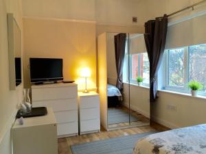 Un dormitorio con un espejo, una cama y un televisor. en Be My Guest Liverpool, en Liverpool