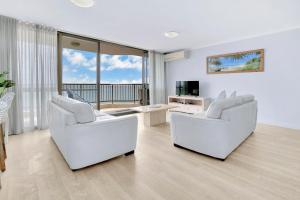 a living room with two white chairs and a television at Seaview Resort in Mooloolaba