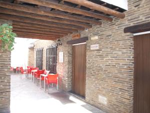 un patio con sillas rojas y una pared de ladrillo en Apartamentos El Mirador en Bérchules