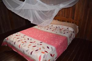 a bed with a red and white comforter with a mosquito net at Casa Hospedaje Tingomaria in Tingo María