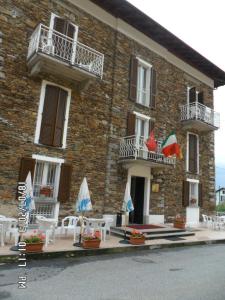 un edificio con sillas y sombrillas delante de él en Il Campanile Hotel - La Cantina Del Pittore, en Miazzina