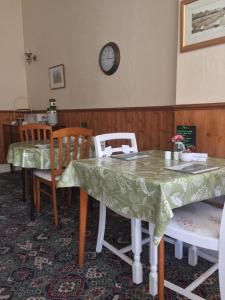 a dining room with a table and chairs and a clock at The Fernside in Sandown