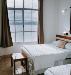 a bedroom with two beds and a large window at Hotel Casa Amelia in Flores