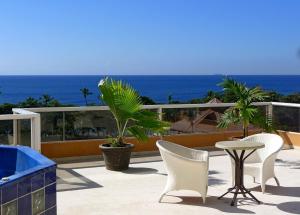 eine Terrasse mit Stühlen, einem Tisch und Meerblick in der Unterkunft Residence Meridiana in Juan Dolio