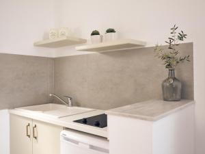 a white kitchen with a sink and a vase with flowers at Villaggio Studios & Apartments in Vasilikos