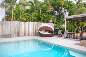 a swimming pool with a grill next to a wooden fence at Moondarah Apartment 6, Noosa Heads in Noosa Heads