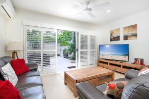 a living room with a couch and a flat screen tv at Moondarah Apartment 6, Noosa Heads in Noosa Heads