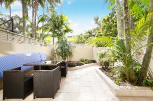a patio with a table and chairs and palm trees at Moondarah Apartment 6, Noosa Heads in Noosa Heads