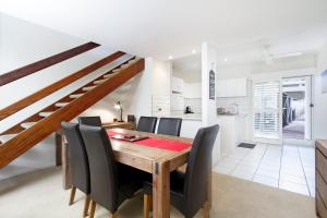 a kitchen and dining room with a wooden table and chairs at Moondarah Apartment 6, Noosa Heads in Noosa Heads
