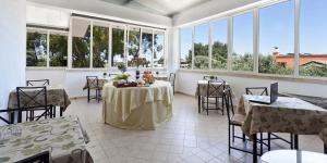 a large room with tables and chairs and windows at Hotel La Campana in Casarano