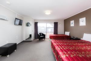 una habitación de hotel con 2 camas y una silla en Manfeild Park Motel, en Feilding