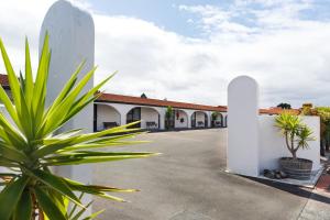 a parking lot with a white building and plants at Manfeild Park Motel in Feilding