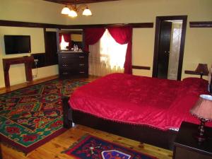 a bedroom with a red bed and a rug at Guest House Bujtina Leon in Korçë