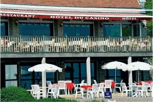 a bunch of chairs and umbrellas in front of a hotel at Logis Hotel Du Casino Restaurant Le Mathelia in Vierville-sur-Mer