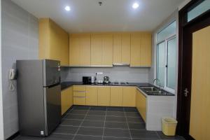 uma cozinha com armários amarelos e um frigorífico de aço inoxidável em Imperial Suites Miri , Diamond Tower em Miri