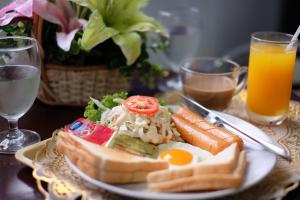 a plate of food with eggs sausage and vegetables and drinks at Happyland Mansion in Bangkok