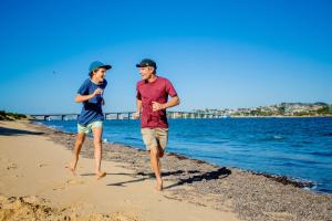 un hombre y una mujer corriendo por la playa en BIG4 Ingenia Holidays Phillip Island en Newhaven