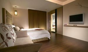 um quarto com uma cama e uma televisão de ecrã plano em Hua Ge Hot Spring Hotel em Jiaoxi