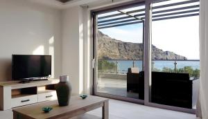 a living room with a television and a large sliding glass door at Beach House in Plakias