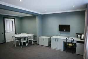 a dining room with a table and a tv on the wall at Olympica Hotel in Almaty