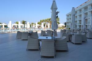 an outdoor patio with tables and chairs and umbrellas at Boyalik Beach Hotel & Spa Cesme in Çeşme