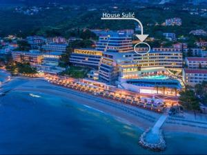 een hotel op een strand 's nachts met een bord dat huissuite leest bij Apartman Sulić in Podgora