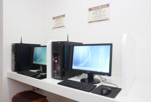 two computer monitors and a keyboard and mouse on a shelf at Hanabi Hotel in Tokyo
