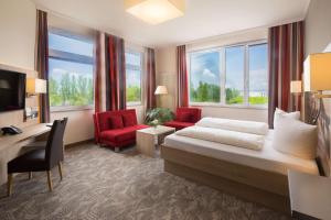 a hotel room with a bed and two red chairs at Best Western Hotel Dreiländerbrücke Weil am Rhein / Basel in Weil am Rhein