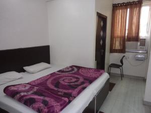 a bedroom with a bed with a purple blanket on it at Hotel Gem Palace in Jaipur